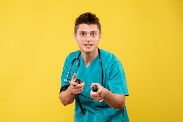 健康身穿医疗服的男医生在黄色墙壁上检查压力的正视图检查听诊器医疗
