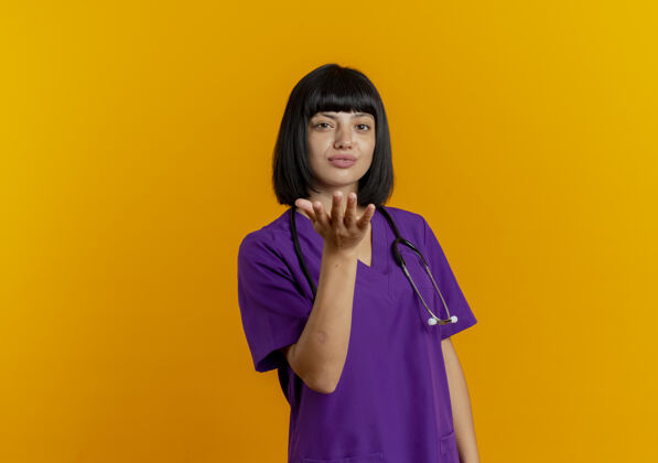 女性自信的年轻黑发女医生穿着制服用听诊器用手送吻年轻复制空间