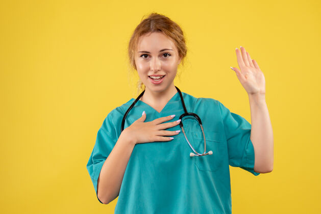 女医生黄色墙壁上穿着带听诊器的医疗服的女医生的正视图医疗医生听诊器