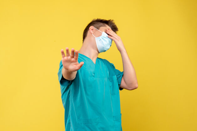 肖像黄墙上的男医生穿着医疗服 戴着无菌口罩健康医学套装