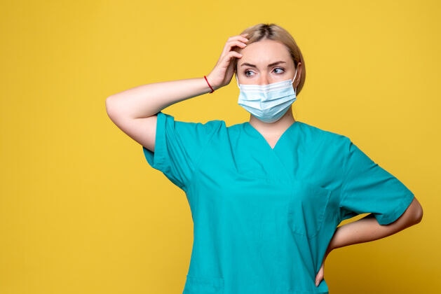 流行病黄墙上年轻女医生穿着医用衬衫 戴着口罩的正面图正面成人医院