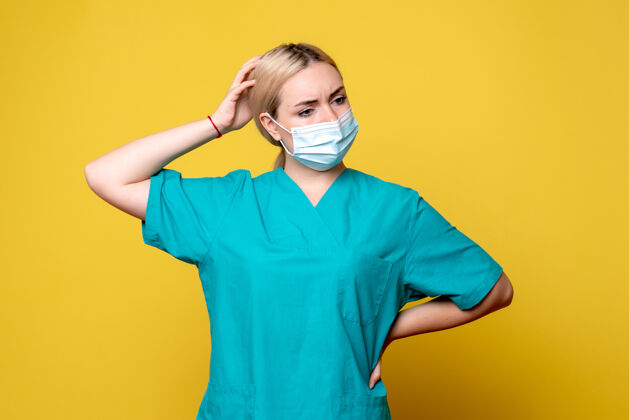 成人黄墙上年轻女医生穿着医用衬衫 戴着口罩的正面图男性人流行病