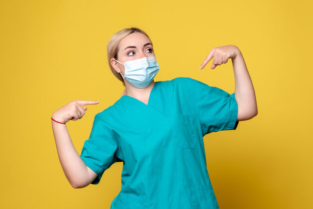 肖像黄墙上年轻女医生穿着医用衬衫 戴着口罩的正面图流行病人人