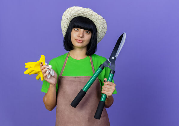 女自信的年轻女园丁穿着制服戴着园艺帽拿着剪刀和手套帽子年轻空间