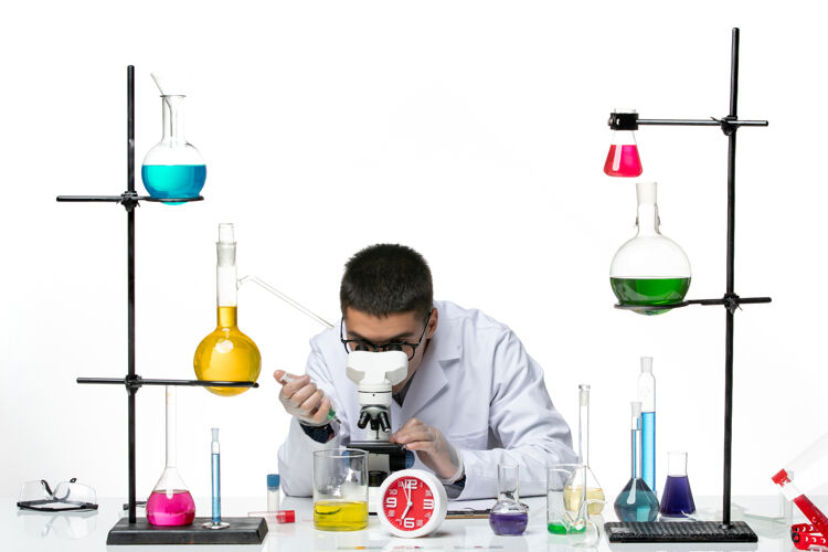 化学前视图身穿白色医疗服的男性化学家在白色背景上用显微镜工作病毒科学冠状病毒-大流行实验室实验室科学实验室