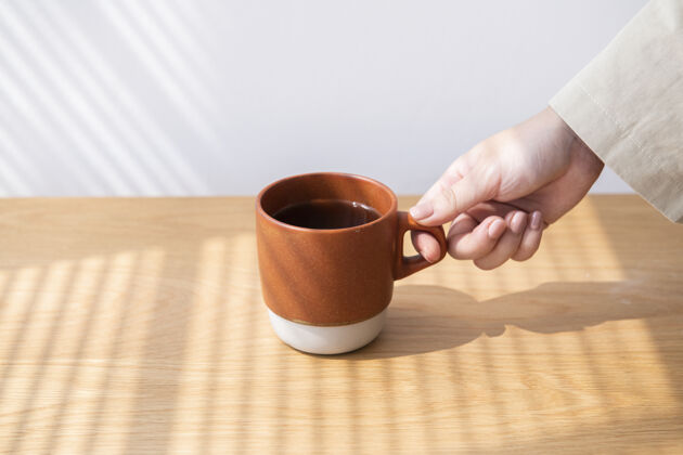 人从木桌上拿咖啡杯的女人咖啡休息最小的家具木制家具