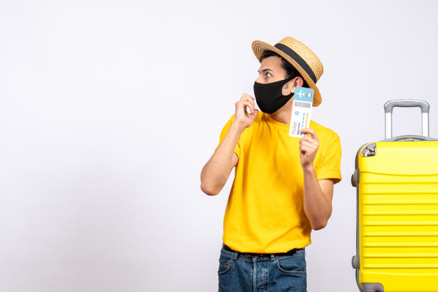 男性游客正面图戴草帽的男游客站在黄色手提箱旁 手里拿着机票专业人士持有稻草