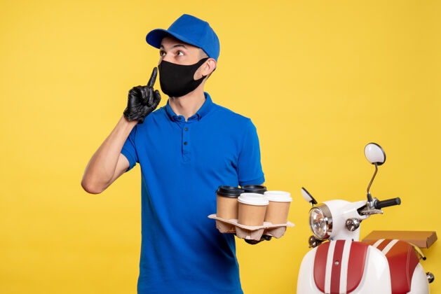 服务正面图身穿蓝色制服 戴着面具的男信使拿着咖啡 穿着黄色工作服 工作服 快递男性信使成人面具
