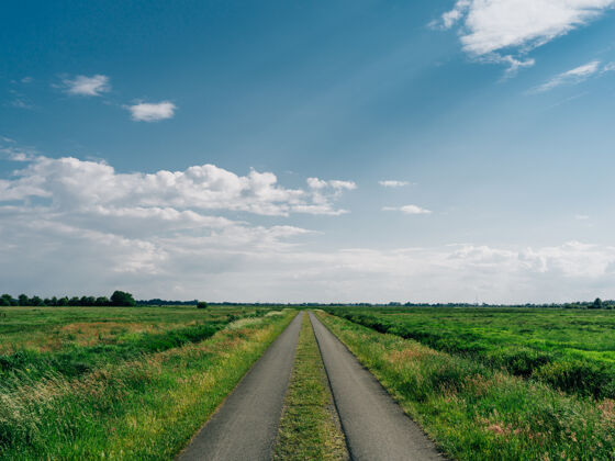 草地在条费尔斯摩的蓝天下 道路被绿油油的田野包围自然乡村阳光
