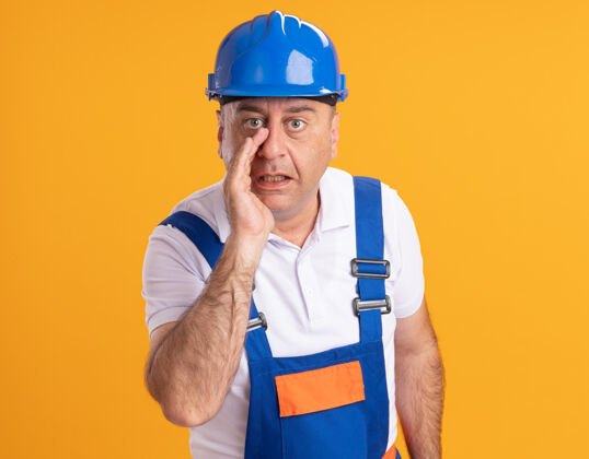 成年人一个穿着制服的白人成年建筑工人惊讶地用手捂住橘子的嘴人惊喜人