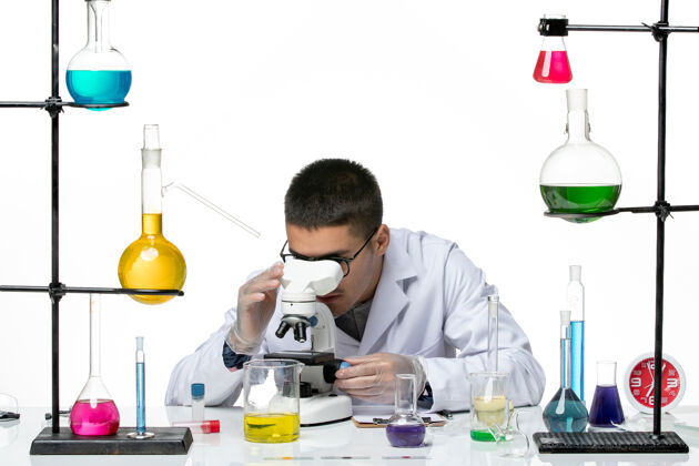 疾病前视图男性化学家穿着白色医疗服 在白色背景上使用显微镜病毒实验室共患疾病科学医疗人正面