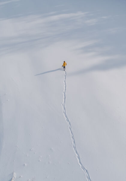 背景鸟瞰一个人行走在一片被雪覆盖的田野高处人雪