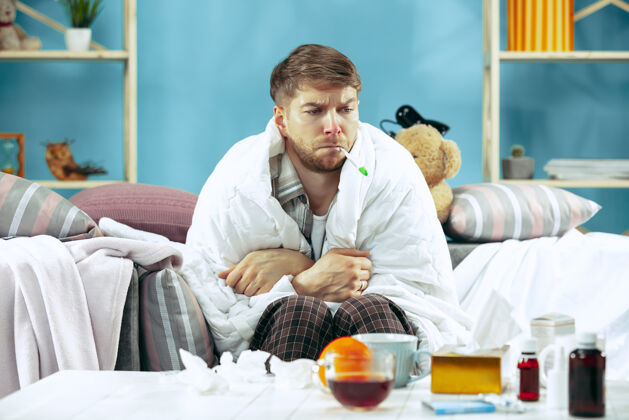 组织留着胡须的病人坐在家里的沙发上测量体温冬天 疾病 流感 疼痛的概念在家放松保健的概念感冒咳嗽男性