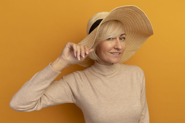 斯拉夫人漂亮的金发斯拉夫女人戴着沙滩帽 戴着橙色的帽子拜托帽子海滩