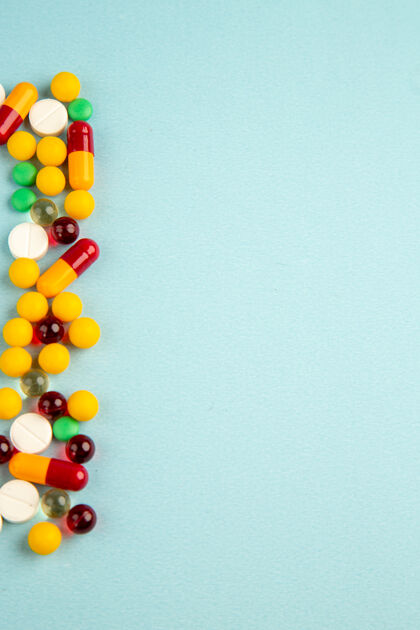 实验室俯视图蓝色背景上不同颜色的药丸顶部大流行药物