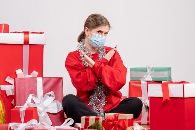 肖像正面图：年轻女性戴着无菌面具坐着 手里拿着圣诞礼物病毒生活面具