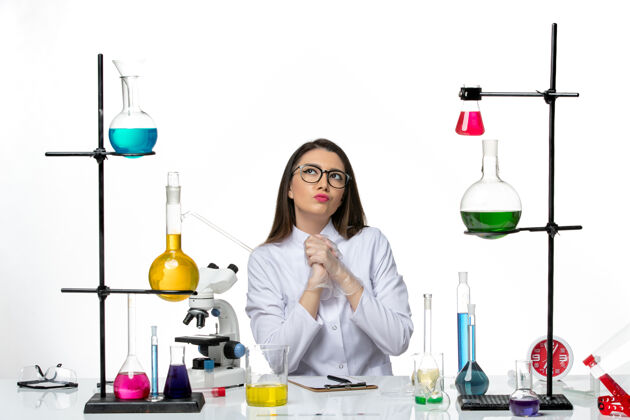 思维前视图穿着白色医疗服的女化学家坐在白色背景上思考实验室科学病毒冠状病毒大流行实验瓶子实验室