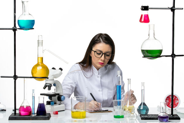实验室前视图穿着白色医疗服的女化学家在白色背景上工作和写笔记科学病毒冠状病毒-大流行实验室罐子视图笔记