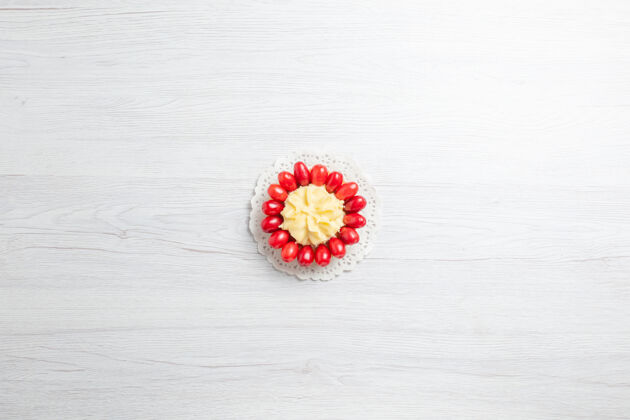 甜点白色书桌上有一块奶油蛋糕和红山茱萸水果花桌子