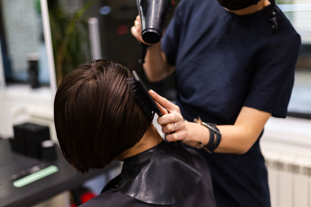 面膜一个专业的女理发师给客户理发这个女孩戴着面具坐在美容院里发廊理发师肖像