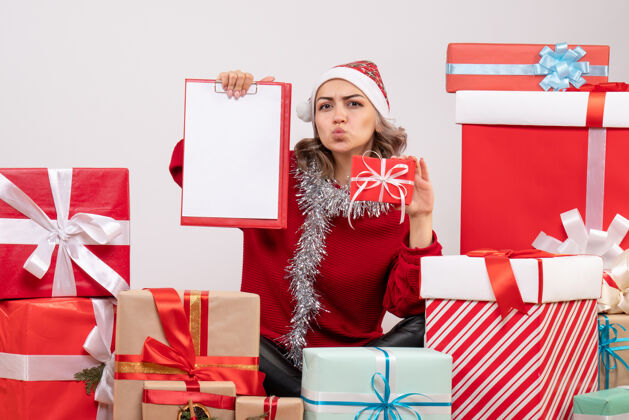 购物正面图年轻女性围坐在圣诞礼物旁 带着纸条人漂亮女人