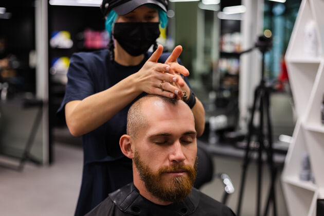 理发师专业美发师戴着防护面罩 在美容院为欧洲胡须野蛮男子理发理发师顾客修剪