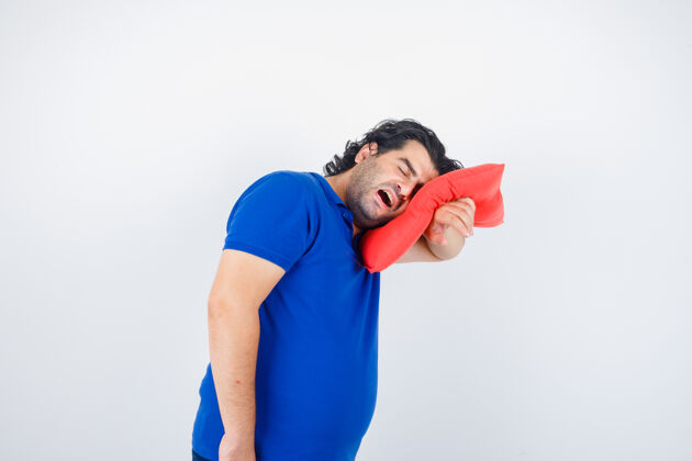 嘴穿着蓝色t恤的成熟男人把头靠在枕头上打哈欠 看起来很困 正面视图疲倦睡觉时间睡衣