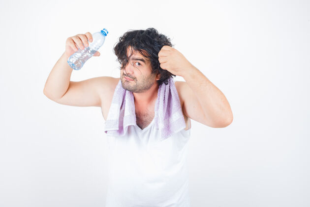 成熟中年男子在背心上 用毛巾托着一缕头发 一边拿着水瓶 看上去很搞笑 前视图前面成人搞笑