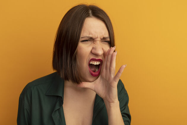 黑发恼怒的白种女人把手紧握在嘴边假装在叫一个正在看橙色的人姿势侧身手