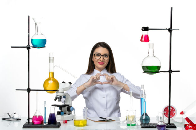 病毒前视图穿着白色医疗服的女化学家坐在白色背景上微笑着实验室科学病毒柯维德大流行视图正面液体