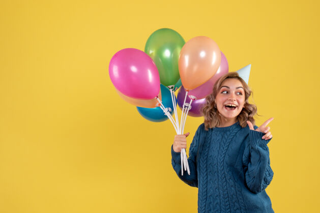一年正面图：带着彩色气球的年轻女性年轻的女性五彩纸屑生日