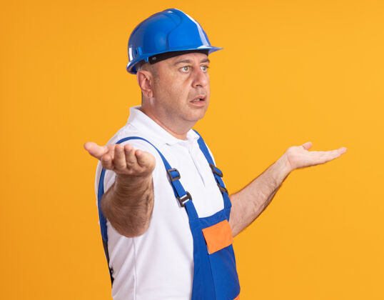 建筑工人焦急的白人成年建筑工人身穿制服站在一旁 手张开放在橘子上制服站着男人