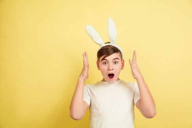 耳朵白人男孩作为复活节兔子在黄色背景上复活节快乐的问候美丽的男模背景问候男性