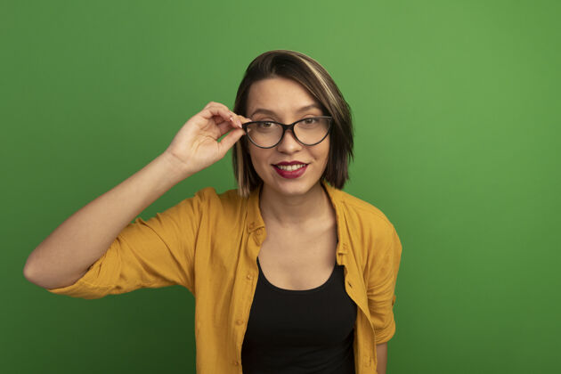 女人一个微笑着的白种女人透过绿色的眼镜看着相机年轻眼镜姿势