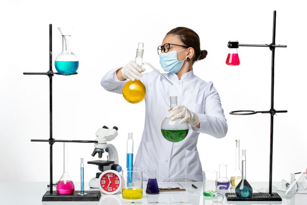 飞溅前视图穿着医疗服的女化学家 戴着面罩 在浅白色背景上工作 病毒化学实验室covidsplash化学药前面