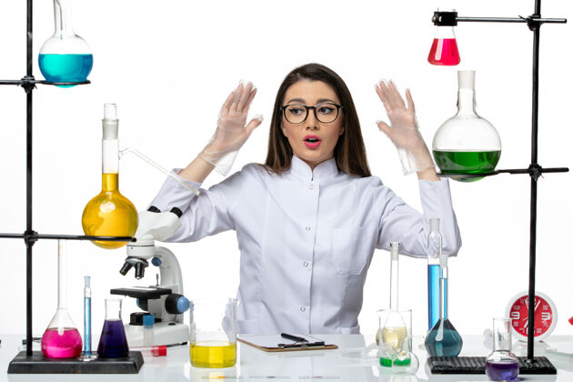 办公桌前视图穿着白色医疗服的女化学家坐在白色办公桌上实验室科学病毒柯维德大流行前台医学医学