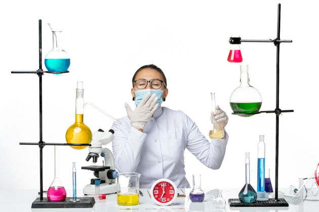面具前视图：穿着白色医疗服的女化学家 在白色背景上戴着面罩 化学家实验室的病毒冠状病毒-飞溅医学持有化学