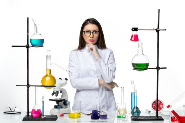 西装正面图：穿着无菌医疗服的女化学家站在桌子旁 拿着白色背景病毒疾病的解决方案-实验室大流行科学医药桌子解决方案