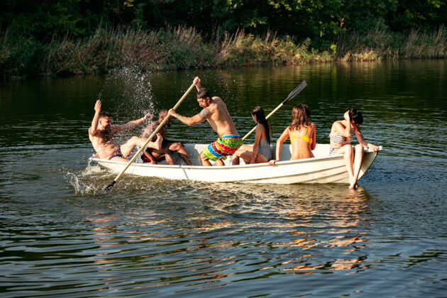 一起一群快乐的朋友在河里欢笑和游泳阳光明媚的日子里 穿着泳装的男女们在河边乘船欢庆夏日 友谊 度假 周末的概念海滩飞溅青年