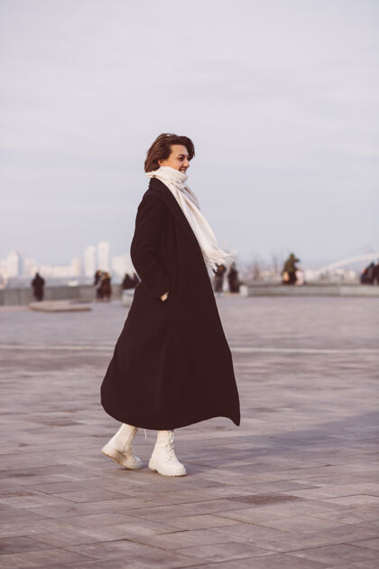 时尚城市广场上穿着冬衣白围巾的女人的画像休闲优雅外套