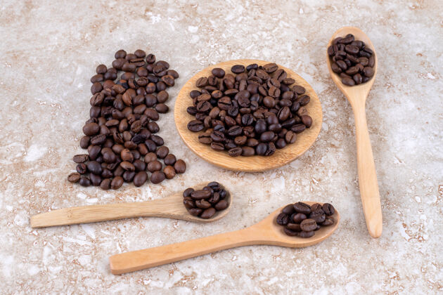 三叉戟把咖啡豆放在勺子上 一个三角架和一小堆美味咖啡豆