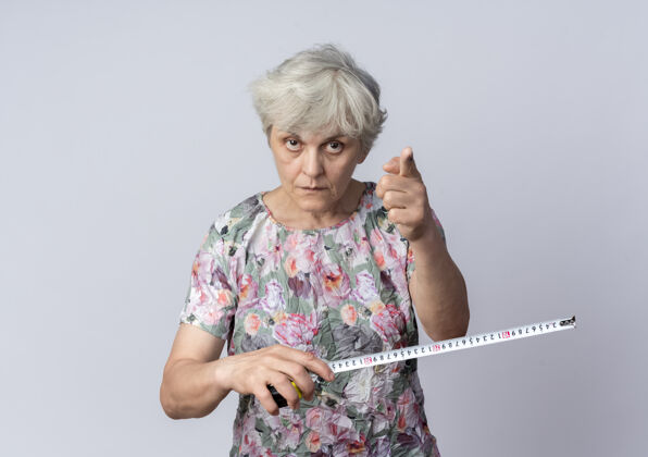 测量自信的老妇人拿着卷尺 在白墙上孤立地点着磁带信心老人