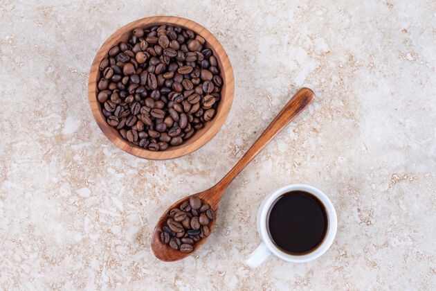 勺子把咖啡豆放在碗里 放在勺子上 旁边放一杯咖啡碗美味咖啡