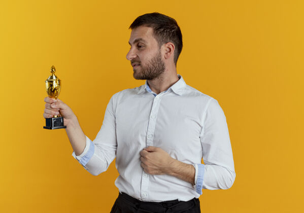 商务男士自信的帅哥拿着冠军杯 看着隔离在橙色墙上的奖杯衬衫橙色帅哥