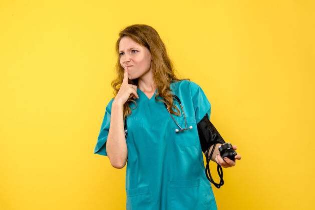 医学女医生在浅黄色墙壁上测量压力的正视图女士人模特