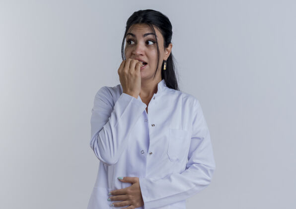 女人焦急的年轻女医生穿着医用长袍 一边看着一边把手放在肚子上 一边咬着手指穿年轻人腹部