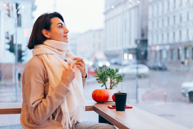 杯子一个女孩在舒适的咖啡馆里用一杯热咖啡取暖女人冬天热