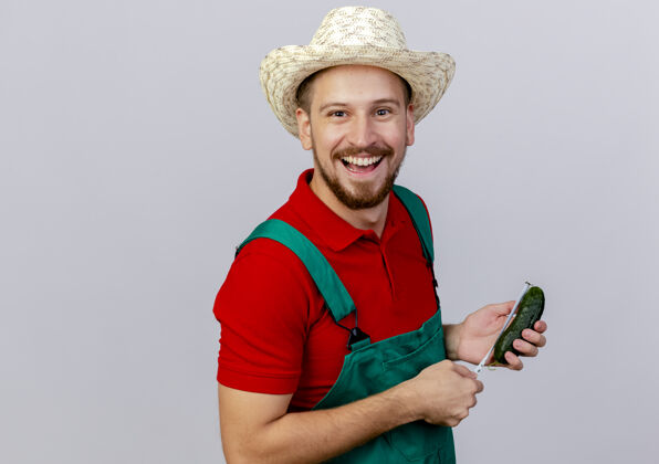 抱着快乐的年轻英俊的斯拉夫园丁穿着制服 戴着帽子 手里拿着黄瓜和卷尺测量黄瓜斯拉夫人米人