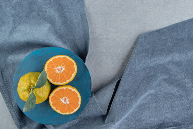 叶把整个橘子切成片放在一块布上的蓝板上 放在大理石上营养有机柑橘