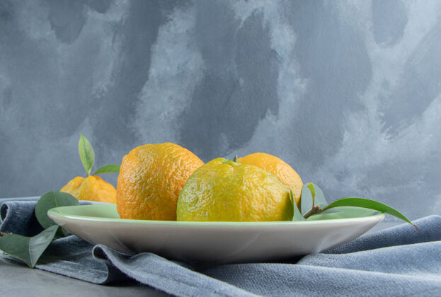盘子把橘子和叶子放在大理石上的盘子里有机水果风味